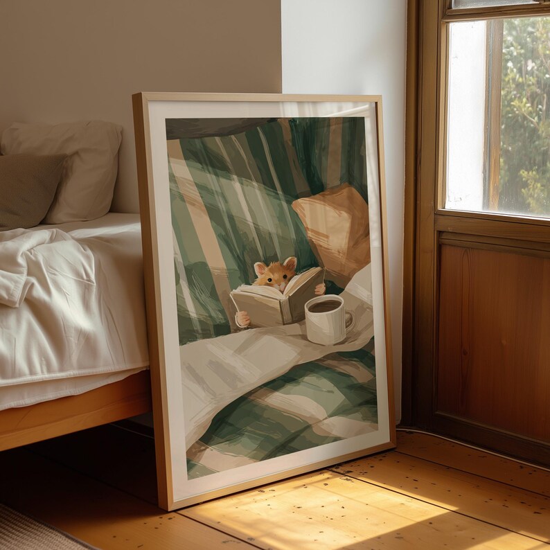 Pu&ograve; includere: Stampa artistica incorniciata con un'illustrazione di un criceto che legge a letto. L'opera presenta una coperta a righe verdi e bianche, un cuscino marrone e una tazza bianca con caff&egrave;. La cornice &egrave; color legno chiaro.