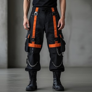 May include: Black cargo trousers with orange straps and accents, featuring multiple pockets and silver chain details. The trousers are paired with a black t-shirt and black boots. The style is modern and edgy.
