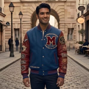 May include: Blue and burgundy varsity jacket with the text "METROPOLIS DIVISION" and a large "M" on the chest. The jacket has multiple patches and the text "ESTABLISHED 2024". The sleeves are burgundy, and the body is blue.
