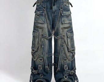 May include: Blue denim cargo trousers with multiple pockets, zips, and silver-tone metal hardware. The trousers feature decorative chains, straps, and buckles, creating a unique, edgy aesthetic. The trousers have a wide leg design.
