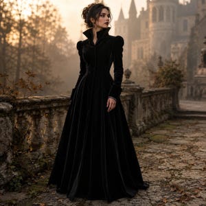 Peut inclure: Une robe manteau longue en velours noir dot&eacute;e d'un col montant, d'&eacute;paules structur&eacute;es bouffantes, de manches longues avec poignets et d'un corsage ajust&eacute; qui se prolonge en une jupe ample et fluide. Le v&ecirc;tement se ferme par des boutons sur le devant.