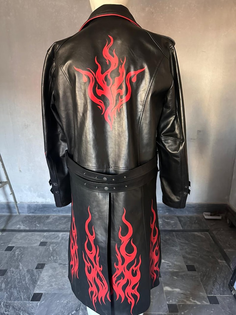 Pu&ograve; includere: Cappotto lungo in pelle nera con disegni di fiamme rosse sulla schiena e sulla parte inferiore anteriore. Il cappotto ha una cintura e finiture rosse. Il cappotto lungo arriva sotto le ginocchia.