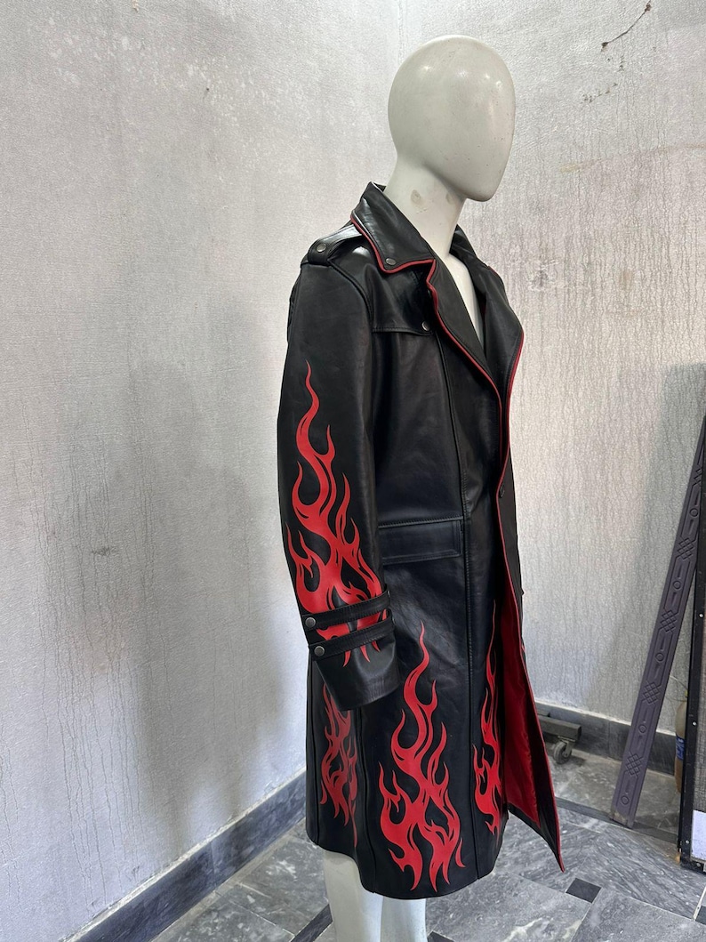 Pu&ograve; includere: Cappotto lungo in pelle nera con disegni di fiamme rosse sulle maniche e sul fondo. Il cappotto ha fodera e finiture rosse ed &egrave; esposto su un manichino. Presenta chiusura con bottoni e colletto a revers.