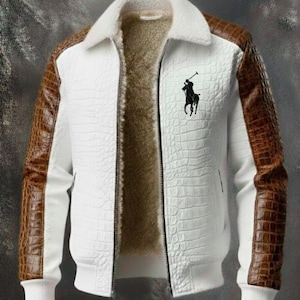 Puede incluir: Una chaqueta blanca con un patrón texturizado de piel de cocodrilo en el frente y mangas con patrón de piel de cocodrilo marrón. La chaqueta cuenta con un cuello de piel sintética blanca, forro de piel sintética beige, cremallera y un logo.