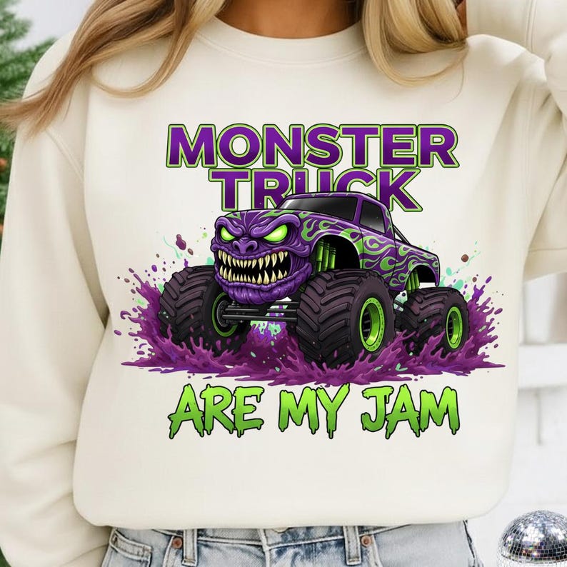 May include: Cream-colored sweatshirt featuring a purple monster truck graphic with green flames and accents. The truck has a menacing face and large tires, with the text "MONSTER TRUCK ARE MY JAM" in green and purple.