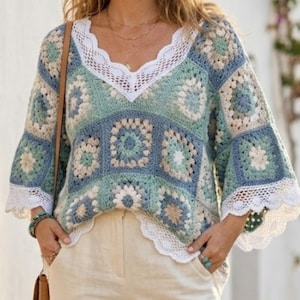 May include: A crochet top in a patchwork design, featuring squares in shades of blue, green, and cream. The top has a V-neckline and bell sleeves, both trimmed with white lace. The overall style is bohemian and handmade.