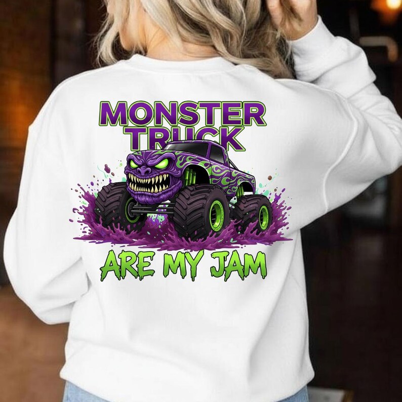 May include: White sweatshirt featuring a purple monster truck graphic with green and purple accents. The text "MONSTER TRUCK ARE MY JAM" is printed above and below the truck design. The truck has large black tires with green rims.