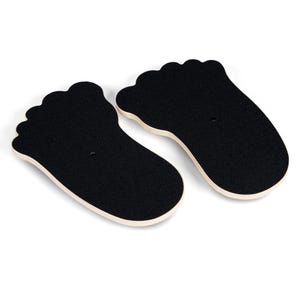 May include: Two black foot-shaped balance boards with a light wood trim. The boards have a textured surface and a small hole in the center. The boards are designed for balance and coordination exercises.
