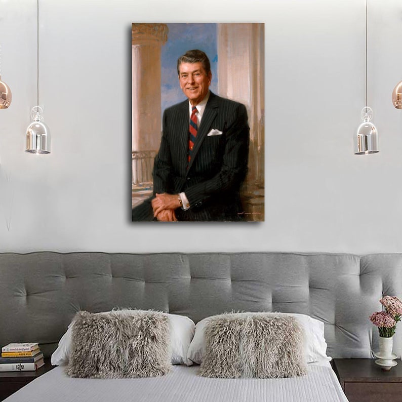 Puede incluir: Retrato enmarcado de un hombre con traje de raya diplom&aacute;tica negro, camisa blanca y corbata a rayas rojas. El retrato est&aacute; ambientado sobre un fondo de columnas cl&aacute;sicas y cielo azul. El hombre est&aacute; sentado, sonriendo, con las manos entrelazadas.