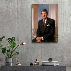 Puede incluir: Retrato enmarcado de un hombre con traje de raya diplom&aacute;tica negro y corbata a rayas rojas y azules. El retrato est&aacute; ambientado sobre un fondo de columnas cl&aacute;sicas y cielo azul. El hombre sonr&iacute;e y parece estar sentado.