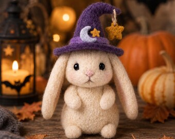 May include: A cream-colored needle-felted rabbit figurine wearing a purple pointed hat. The hat features a light blue crescent moon, a small yellow star, and a dangling yellow star charm. The rabbit has long ears, black eyes, and a pink nose.