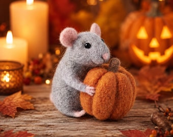 May include: A needle-felted gray mouse figurine with pink inner ears and a pink nose, holding a small, textured orange pumpkin with a brown stem. The mouse has black bead eyes and a soft, fuzzy texture, crafted from wool fibers.