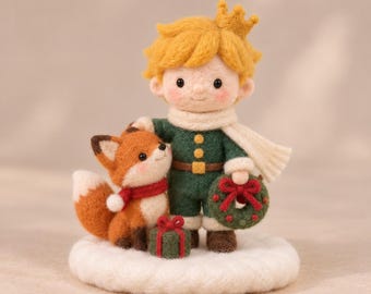 May include: A needle-felted figurine of a boy with yellow hair and a crown, wearing a green outfit and white scarf, standing next to a fox with a red scarf. The boy holds a green wreath with a red bow, and a small green gift box sits on the white base.