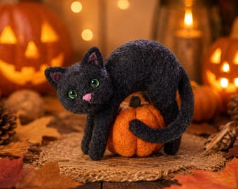 May include: A needle-felted black cat figurine with bright green eyes and a small pink nose, arched in a playful stance while standing over a miniature orange pumpkin. The cat has a textured, fuzzy appearance and a long, curved tail.