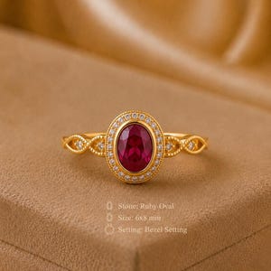 Könnte beinhalten: Ein Goldring mit einem zentralen 6x8 mm großen ovalen Rubin in Zargenfassung, umgeben von einem Kranz aus kleinen weißen Steinen. Die Ringschiene hat ein filigranes, durchbrochenes gedrehtes Design. Text: Stone: Ruby Oval, Size: 6x8 mm, Setting: Bezel Setting.