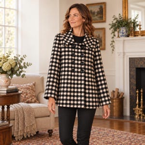 May include: A black and white houndstooth patterned jacket featuring a wide collar, long sleeves, and a double-breasted front closure with large black buttons. The jacket is worn over a solid black top and black trousers, creating a classic look.