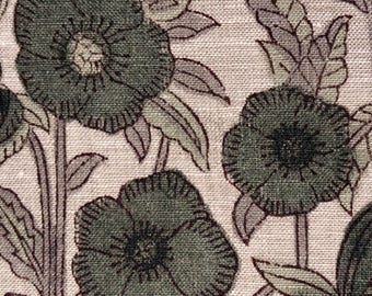 Op de afbeelding: Close-up van een stof met een bloemenpatroon. Het ontwerp toont grote, donkergroene bloemen met gedetailleerde contouren en centra, tegen een lichtbeige achtergrond. Bladeren in groen- en grijstinten vullen de bloemelementen aan.