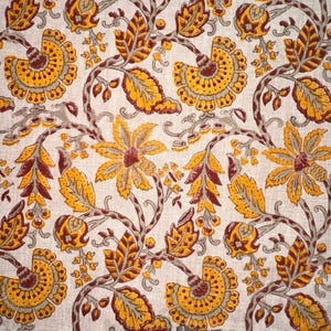May include: Floral fabric with a repeating pattern of stylized flowers and leaves in shades of yellow, brown, and gray on a cream background. The design features large, detailed blossoms and winding vines.