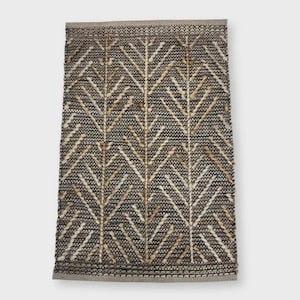 May include: Rectangular rug with a geometric pattern. The rug has a dark grey background with a repeating design of light beige chevron-like shapes. The border is a solid light grey. The rug is made of woven material.