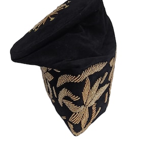 May include: A black cap with gold-colored embroidered floral designs. The cap features a curved brim and is decorated with intricate gold beadwork. The cap's design includes a gold floral pattern on the top and around the base.