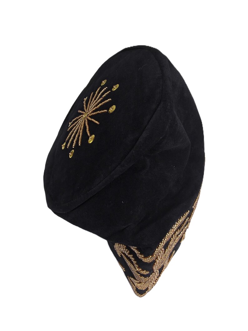 May include: Black beret-style hat with gold embroidered accents. The hat features a starburst design on the crown and ornate detailing along the brim. The hat is made of a soft, dark fabric.