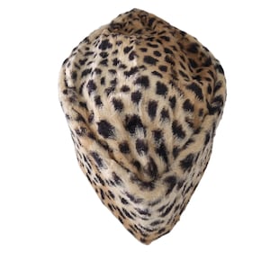 May include: A faux fur hat with a leopard print pattern. The hat features a beige base color with black spots, creating a spotted design. The hat is a rounded shape.