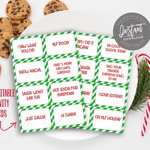 Op de afbeelding: Kerstactiviteitenkaarten met groen-witte randen en rode tekst, met zinnen als "Elf Poop" en "I Love Cookies". Chocoladekoekjes en zuurstokken zijn ook zichtbaar.