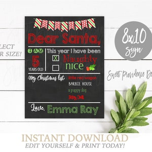 May include: A black chalkboard-style sign with red and green text and graphics. It features a festive banner, the heading Dear Santa, and sections for age, behavior status, and a Christmas list. The sign includes the name Emma Ray.