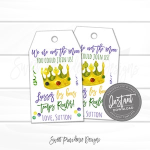 May include: Two white gift tags with a gold crown and purple text. The text reads "We are over the moon YOU COULD JOIN US!" and "Laissez les bons temps rouler! LOVE, SUTTON". The tags are decorated with green, purple, and gold beads.