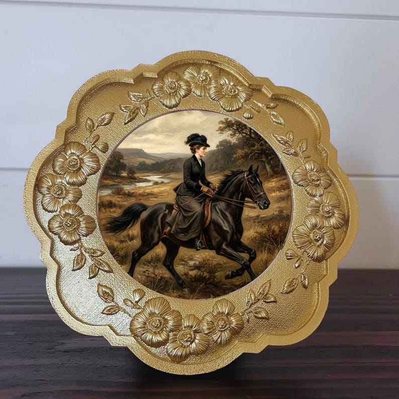 May include: A gold-colored, floral-edged decorative plate featuring a vintage painting of a person riding a black horse through a landscape. The rider is dressed in a dark outfit and hat. The plate has a scalloped edge.