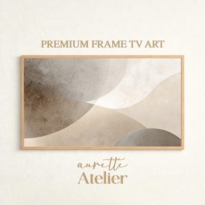 May include: A framed abstract art print with a neutral color palette. The artwork features overlapping, flowing shapes in shades of beige, brown, and gray. The text "PREMIUM FRAME TV ART" and "aurette Atelier" are displayed on the image.
