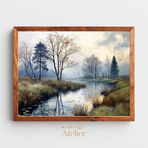 May include: A framed landscape painting depicts a serene waterscape with a reflective river, trees, and grassy banks. The artwork features a muted color palette of blues, greens, and browns, with a wooden frame. The artist's name is visible at the bottom.
