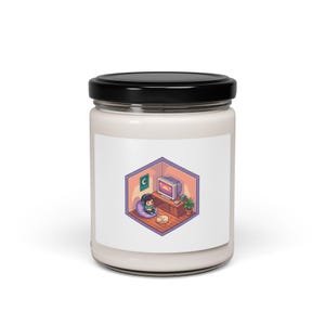 May include: A white candle jar with a black lid. The label features a cartoon illustration of a person in a room with a computer, a cat, and a crescent moon. The room is in a hexagonal shape.