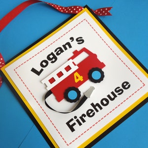 May include: A red and white fire truck with a black hose and a yellow number 4 on the side. The truck is on a white background with black text that says "Logan's Firehouse".