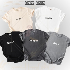 May include: A color chart of five t-shirts in ivory, white, black, pepper, and grey. The shirts are short-sleeved and have a crew neck. The text "Color Chart" is at the top of the image, with the color names printed on each shirt.