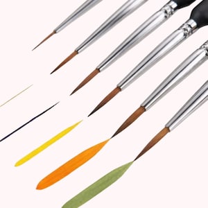 May include: A set of fine-tipped paint brushes with silver metal handles and black grips. The brushes are arranged diagonally, with colorful paint strokes in yellow, orange, and green. The bristles are brown.