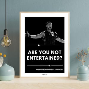 May include: Framed black and white print with a still from the film Gladiator. The image shows a man with outstretched arms, and the text "ARE YOU NOT ENTERTAINED?" below. The print also includes the name "MAXIMUS DECIMUS MERIDIUS - GLADIATOR".