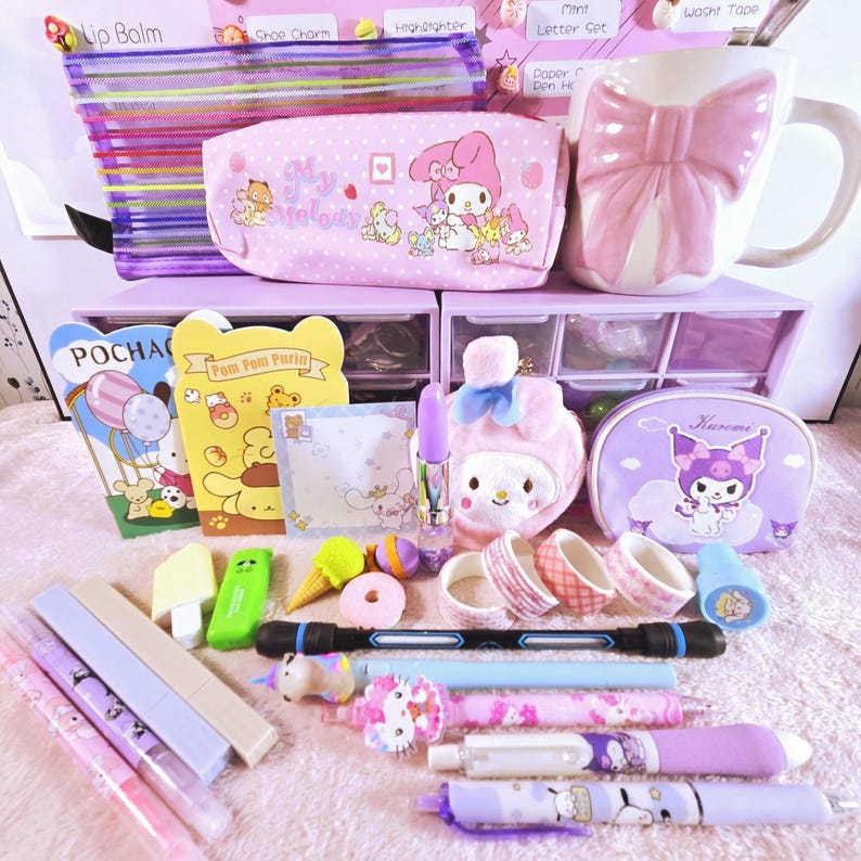 Puede incluir: Una colecci&oacute;n de art&iacute;culos de papeler&iacute;a y accesorios en tonos rosas y morados. Incluye bol&iacute;grafos, l&aacute;pices, una taza con lazo, un estuche, cinta washi y una peque&ntilde;a unidad de almacenamiento. Tambi&eacute;n se ven b&aacute;lsamo labial y un resaltador.