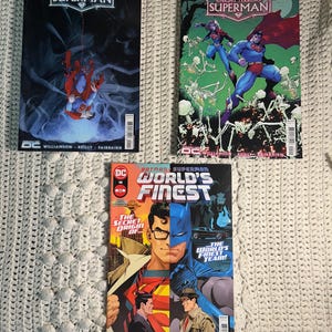 Può includere: Tre fumetti con Superman e Batman. I due fumetti in alto sono della serie "Knight Terrors: Superman", con Superman in pose d'azione. Il fumetto in basso è "Batman Superman: World's Finest", con Superman e Batman fianco a fianco.