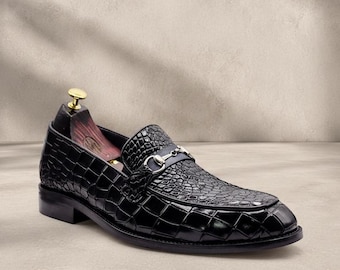 Mocasines de hombre de piel negra con relieve de cocodrilo y detalle de herradura.