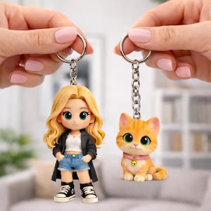 Peut inclure: Deux porte-clés : l'un représentant une poupée blonde vêtue d'une veste noire, d'un short en jean et de baskets, et l'autre un chat tigré orange avec un collier rose et une clochette. Les deux porte-clés sont attachés à des anneaux argentés.