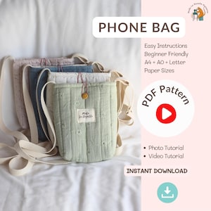 Pode incluir: Uma coleção de bolsas para telemóvel acolchoadas em várias cores pastel, incluindo verde claro, azul e rosa, com alças cor creme. As bolsas têm um padrão floral e uma etiqueta que diz "Mida Le Gazelle". O texto "PHONE BAG" é exibido no topo.