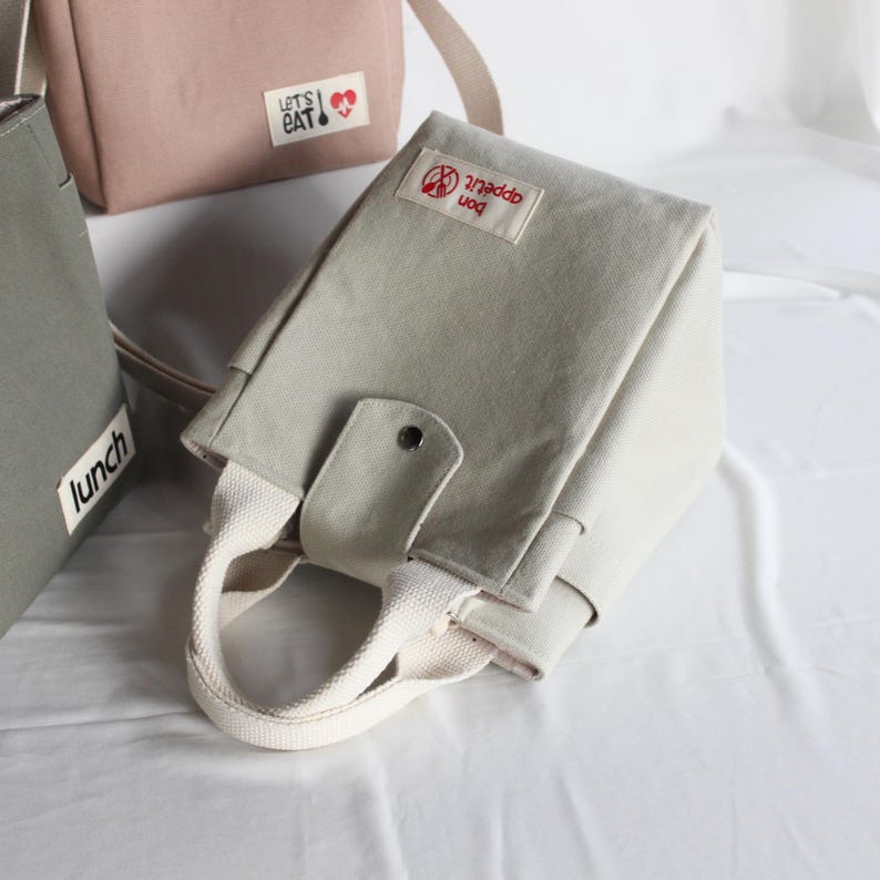 unctional canvas bag with two side pockets holding a water bottle and a coffee tumbler.