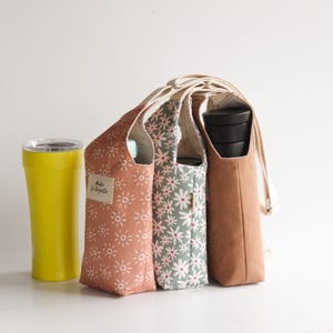 Eco-friendly reusable bottle carrier bag featuring a stylish floral print in sage green and white.
