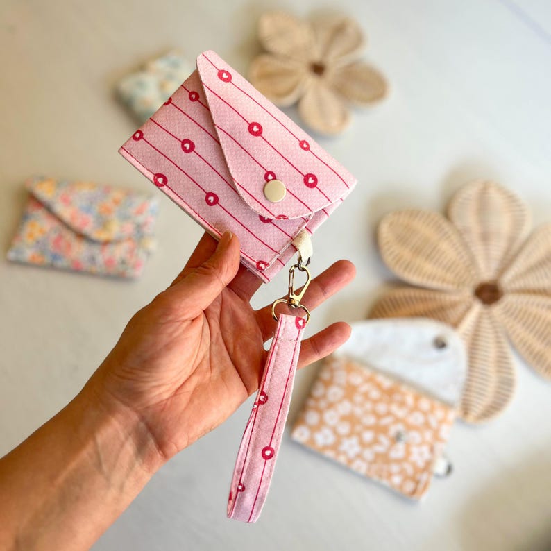 Small snap closure card case with D-ring tab for bag charm use.