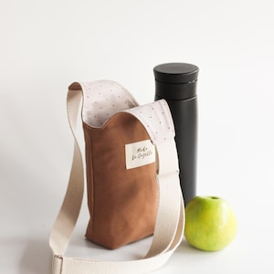 Three different bottle bags hanging on a rack to showcase various fabric pattern options.