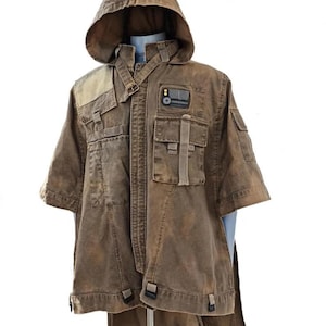 May include: A brown hooded jacket with multiple pockets and a unique design. The jacket has a short sleeve design and a long, flowing tail. It features a patch with a small rectangular design. The jacket is displayed on a mannequin.