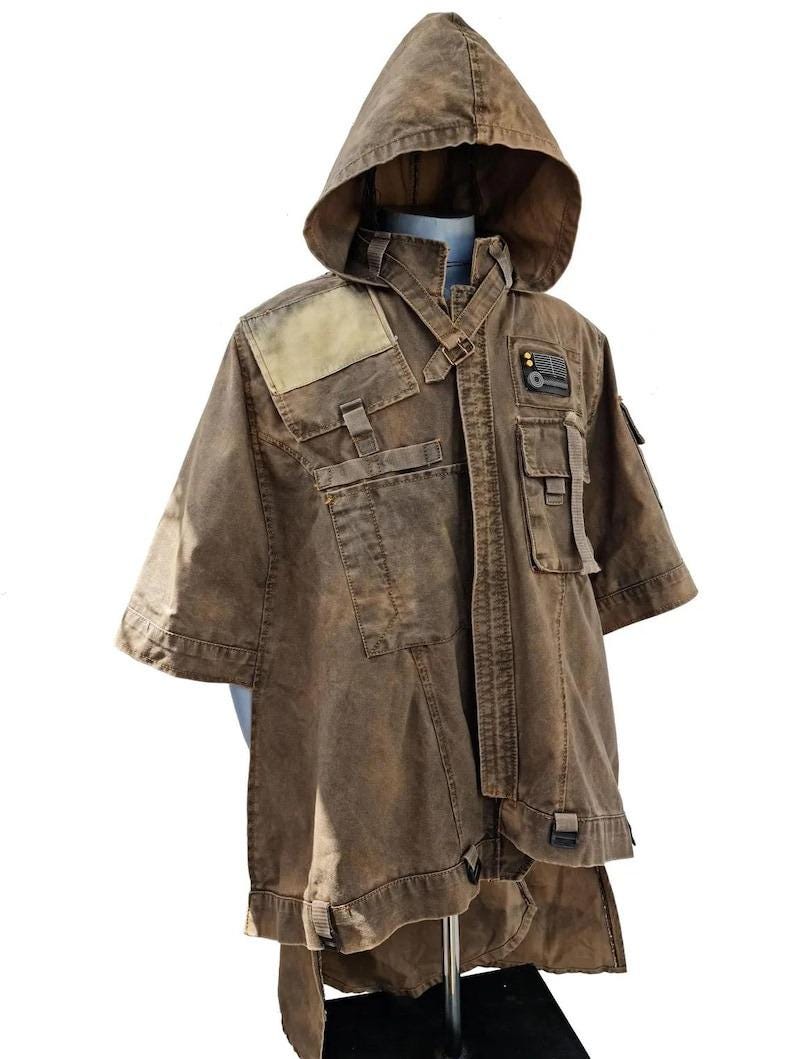 May include: Brown hooded jacket with multiple pockets and straps. The jacket has a unique design with a weathered appearance, featuring a hood and short sleeves. The jacket is displayed on a mannequin, showcasing its details and construction.