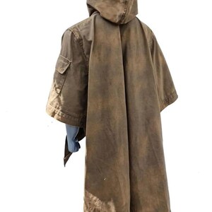May include: A brown hooded poncho with a weathered appearance. The poncho features a large hood, a single pocket on the left side, and a long, flowing design. The fabric has a worn, distressed look, suggesting a vintage or rustic style.