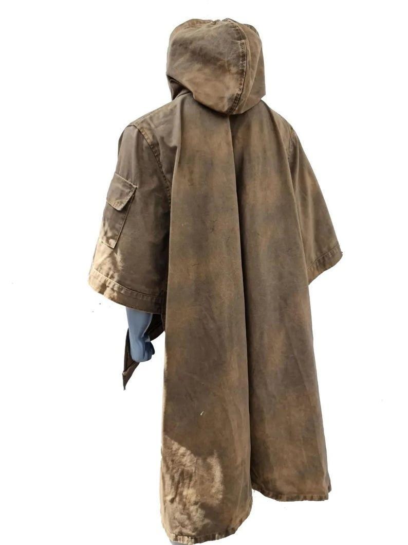 May include: A brown hooded poncho with a weathered appearance. The poncho features a large hood, a single pocket on the left side, and a long, flowing design. The fabric has a worn, distressed look, suggesting a vintage or rustic style.